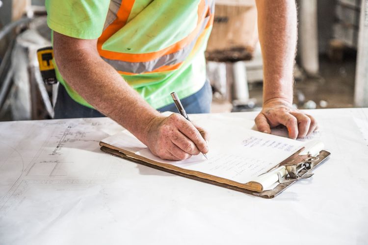 A tradesman writing up a job card on a clipboard